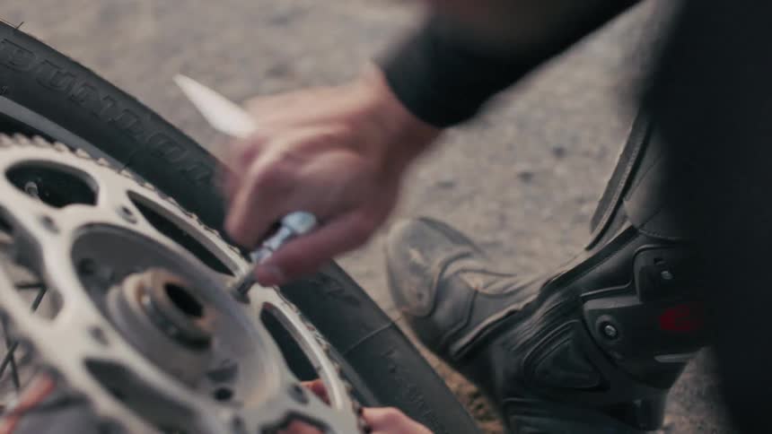 Pair of hands of a person with a tool working on a motorcycle wheel