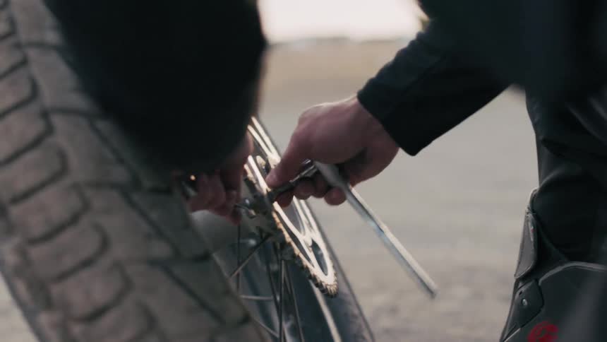 A man uses a socket wrench on his tire