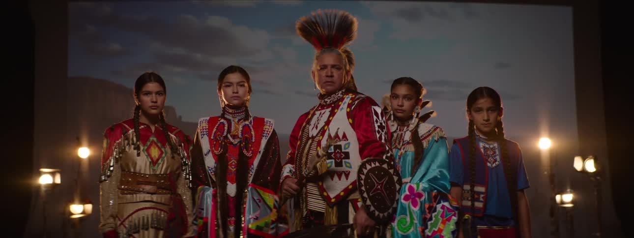 A group stands together while wearing indigenous clothing