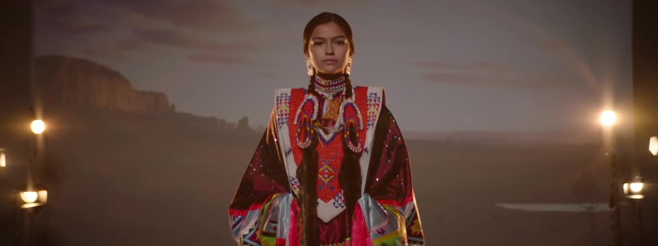 Young woman in traditional indigenous costume in a hall lit with warm lights