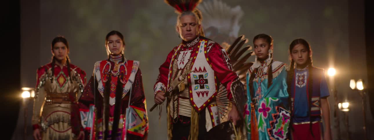 A tribe pose together on stage in costumes