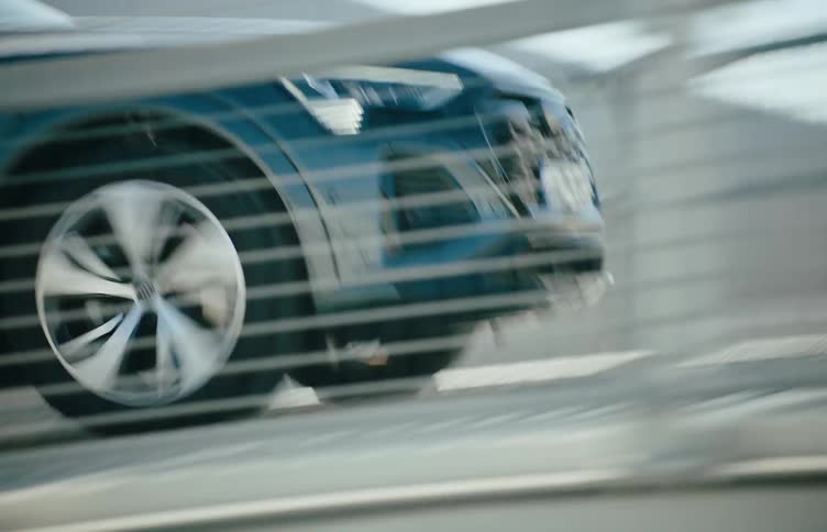 A sedan car driving across a steel bridge on a sunny day