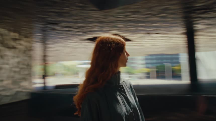 The face of a redhaired woman standing in a dark indoor environment