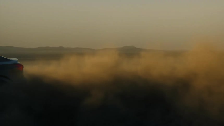 The car is leaving behind a dust cloud in the desert