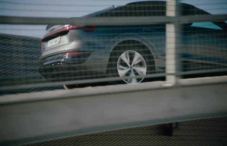 A sleek audi suv drives up a ramp in a sunlit urban parking structure