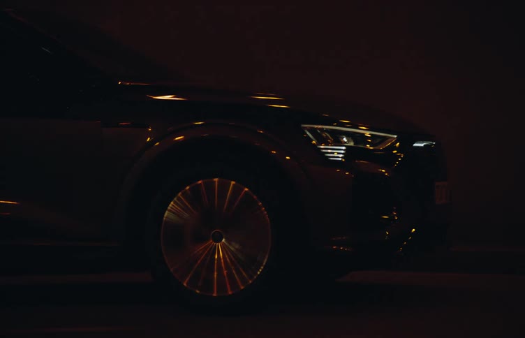 A sleek black electric car is driving through a dimly lit tunnel at night