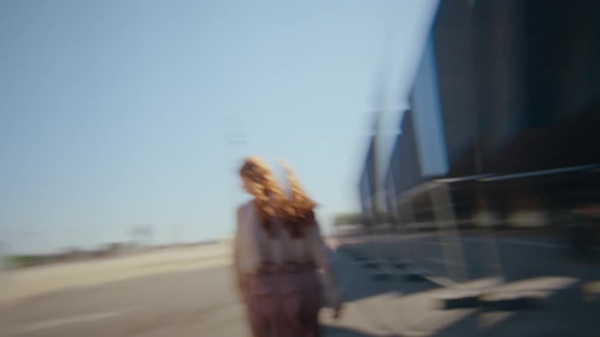 A young woman with red hair steps onto the city sidewalk observing the highrise buildings and skyscraper views at midday