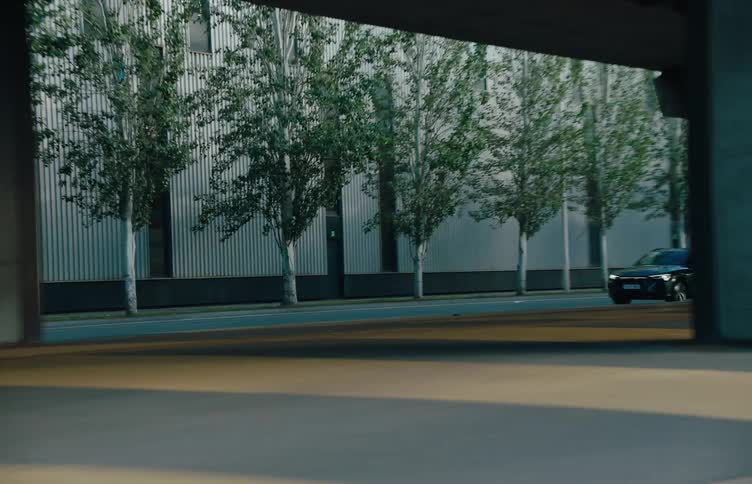 Black car driving on a road next to an overpass through the city