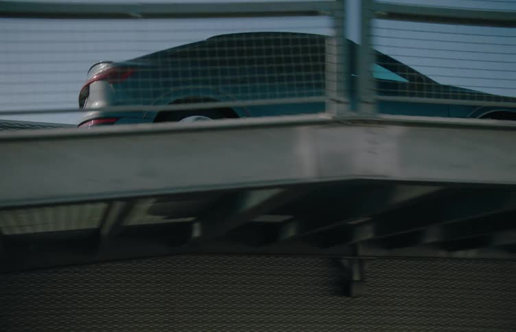 A car is driven over a metal bridge in city during daytime