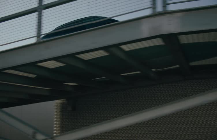 A sedan drives over a steel ramp bridge at midday