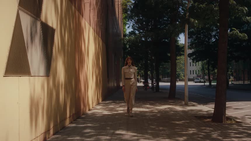 Woman in a white outfit walking on the sidewalk of an urban city