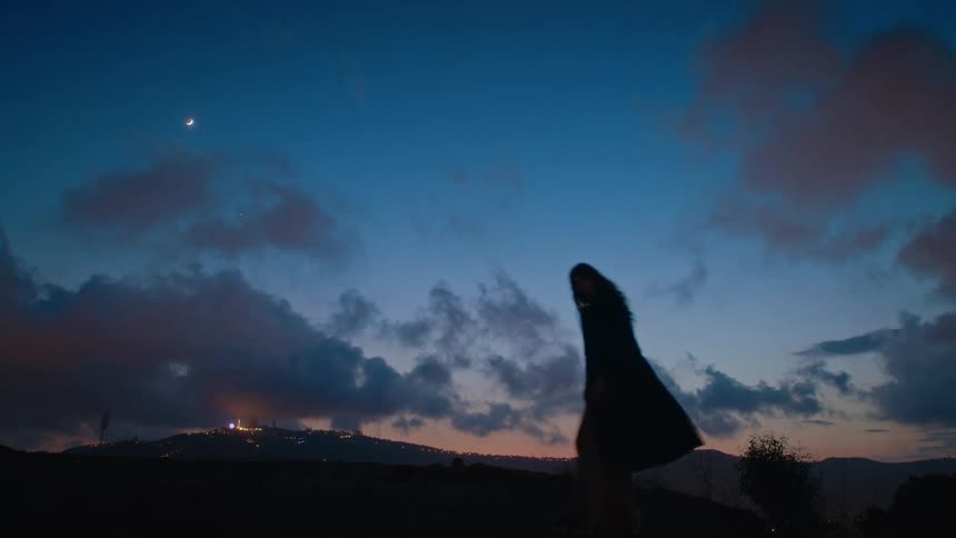 A woman spins on the hill at sunset