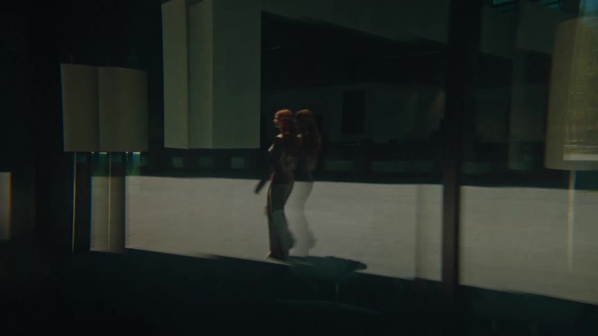 The reflective window of the building shows a woman walking