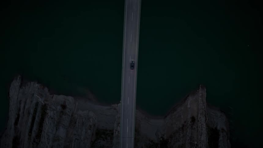 A car drives over a long bridge above canyons and a river