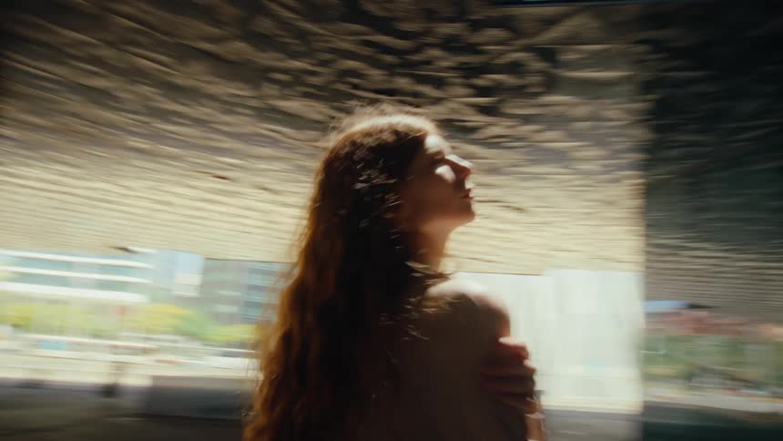 A woman is hugging herself by the building