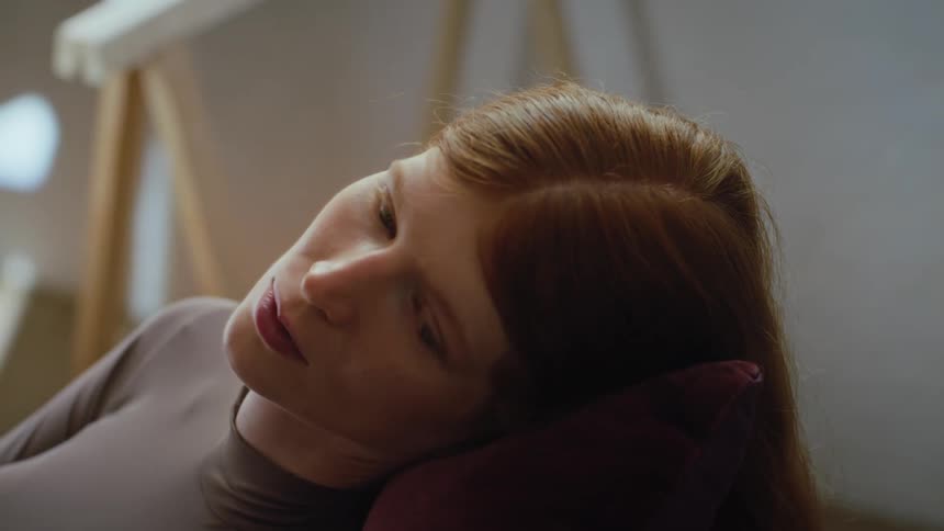 A young woman sitting and resting on a chair indoors at midday