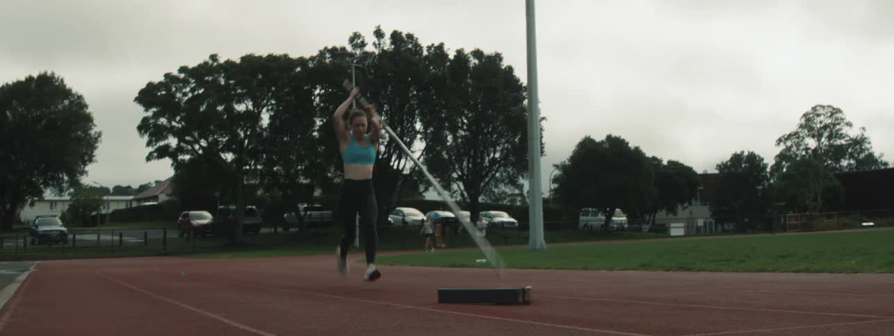 Young female vaulter running on an outdoor track tries to take a vault