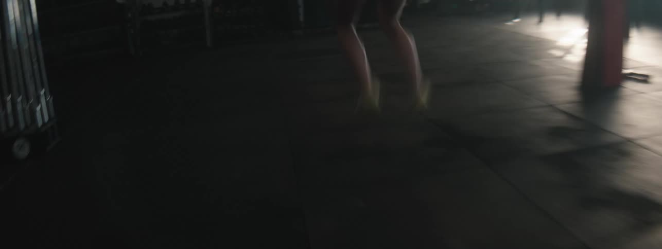 A woman wearing workout clothes is continuously hopping across the floor