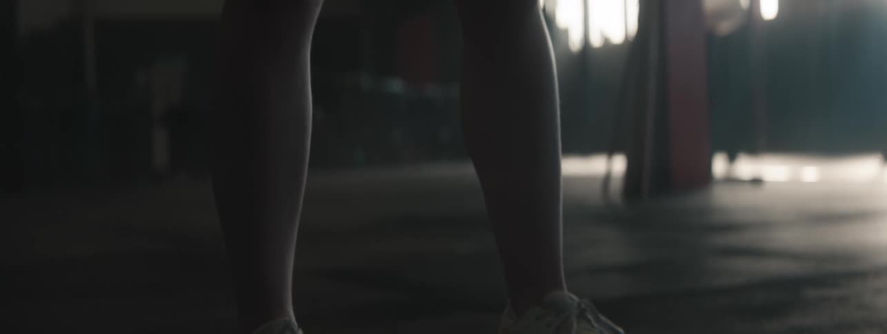 A barbell is deadlifted and quickly dropped bouncing off the floor of a dimly lit gym as it lands