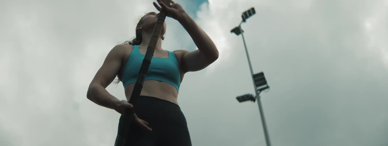 Young female athlete prepares her runup as she practises for pole vault outdoors during the day