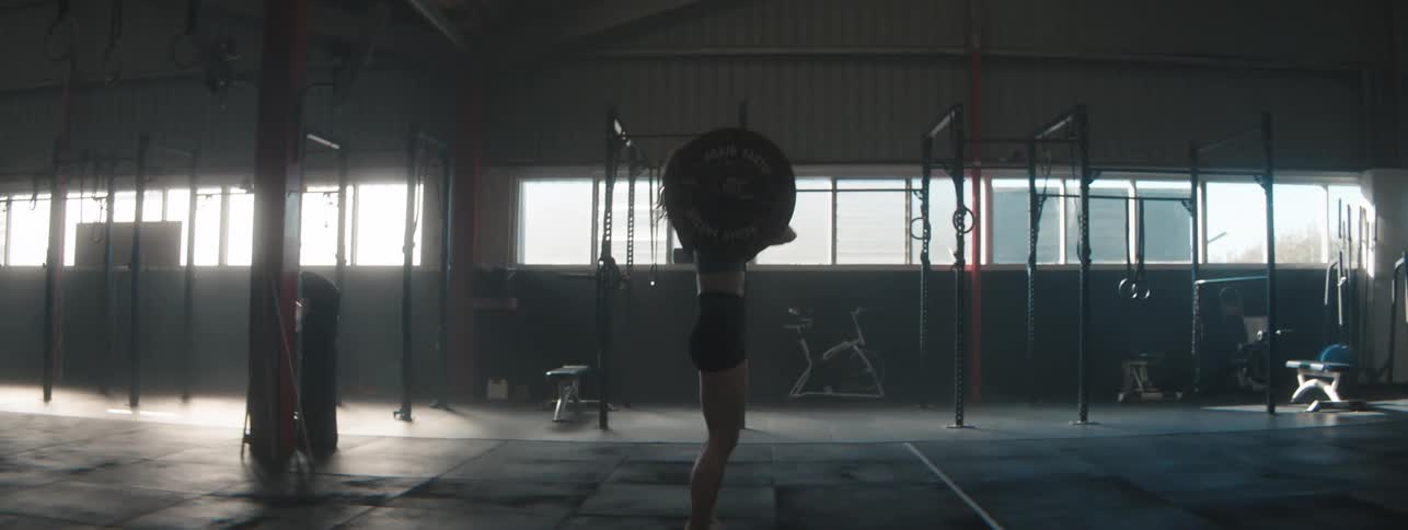 A young woman lifts and drops gym weight in a gym