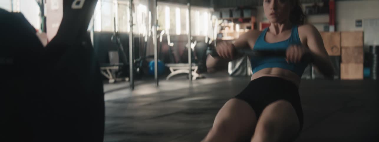 A young woman wearing active pants works out in the gym at midday