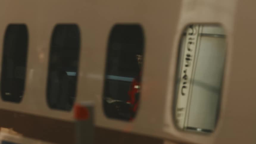 Reflective windows on a passing subway train reflect men standing in uniform