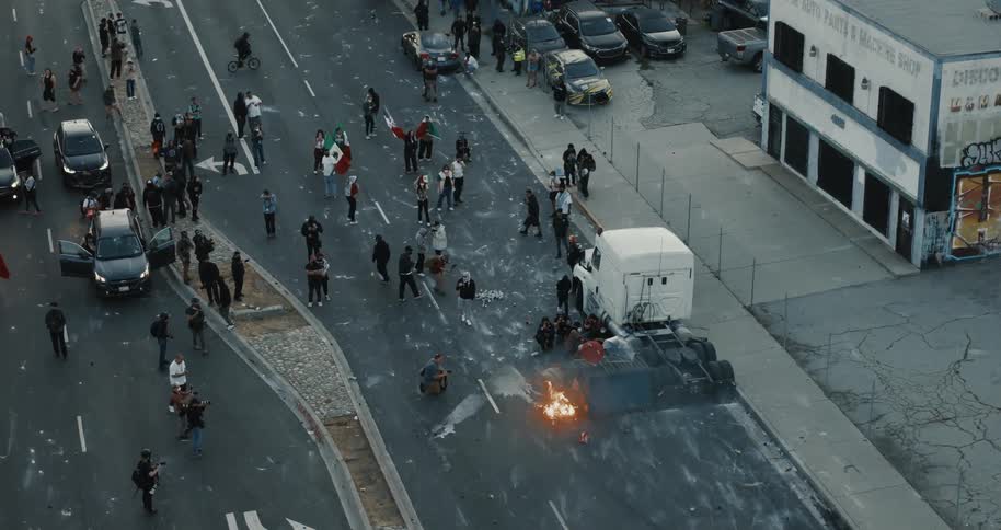 Protesters confront a burning police vehicle amid crowds and officers