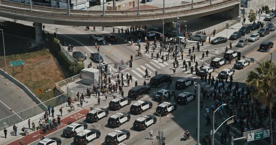 Police cars block protestors from moving down a section of a street