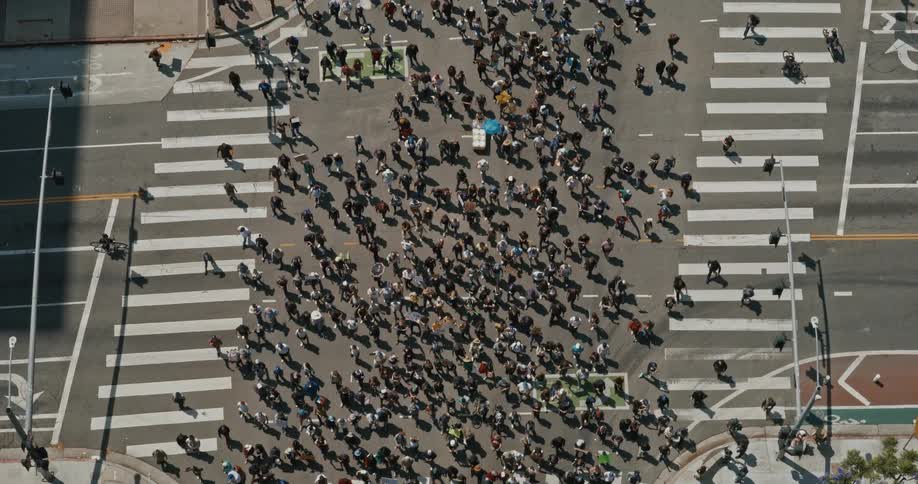 A large protest has many people marching through the intersection