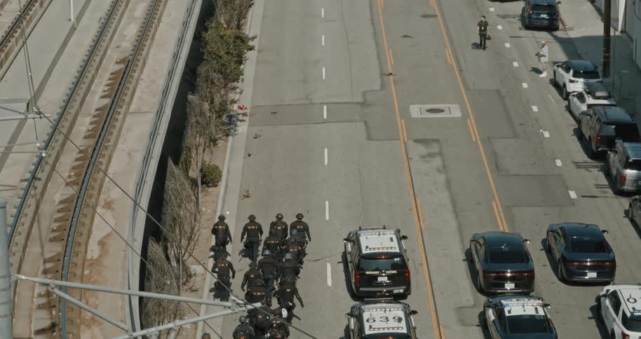Police troop moving towards protesters on an urban road