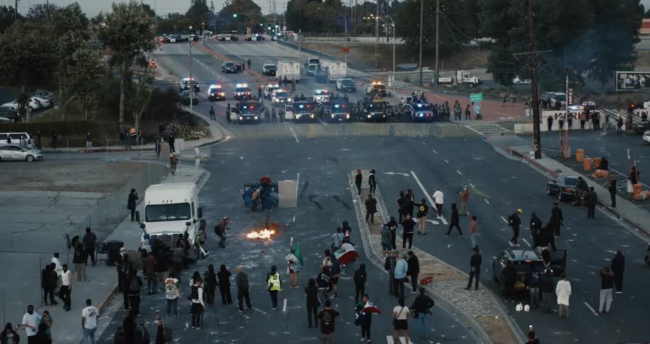 Protesters face a police blockade at dusk amid fires and vehicles