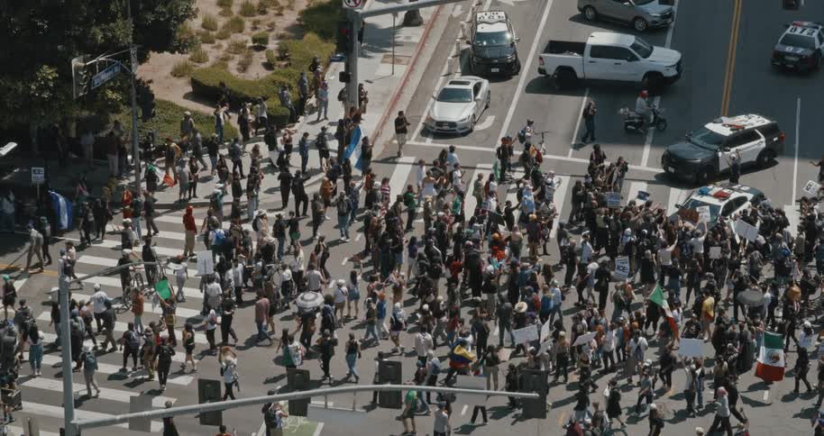 A large crowd of people is gathered in los angeles with visible signs and banners indicating a protest or demonstration