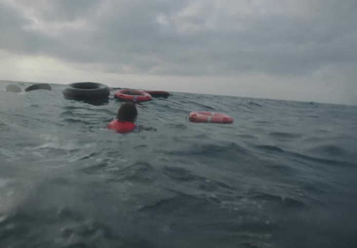 A person swims toward a swim ring in the ocean at midday