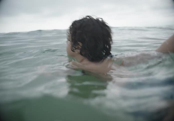 A father holds his son in the water while teaching him how to swim