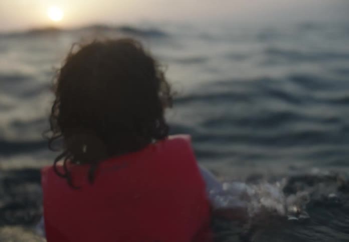 The life jacket is helping the boy swim in the rough water