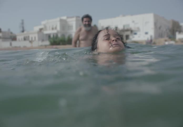 A father watches his son struggle to swim