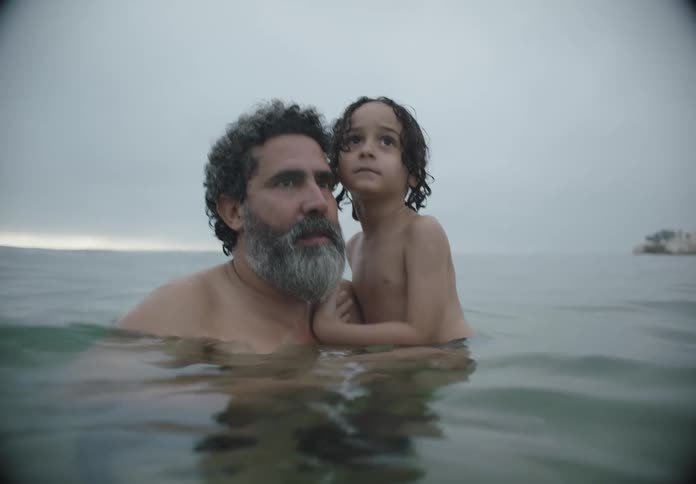 Father and son swim together in a lake during daytime
