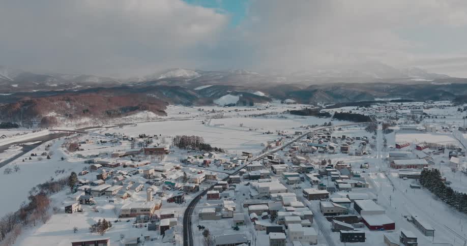 Aerial view of a snow covered suburban neighborhood in front of a mountain range