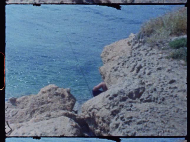 A man is fishing by the rocks