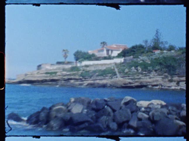 Two people walk beside a vacation house on a coastal promontory