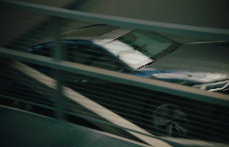 Dark grey sedan drives up a ramp in a parking garage
