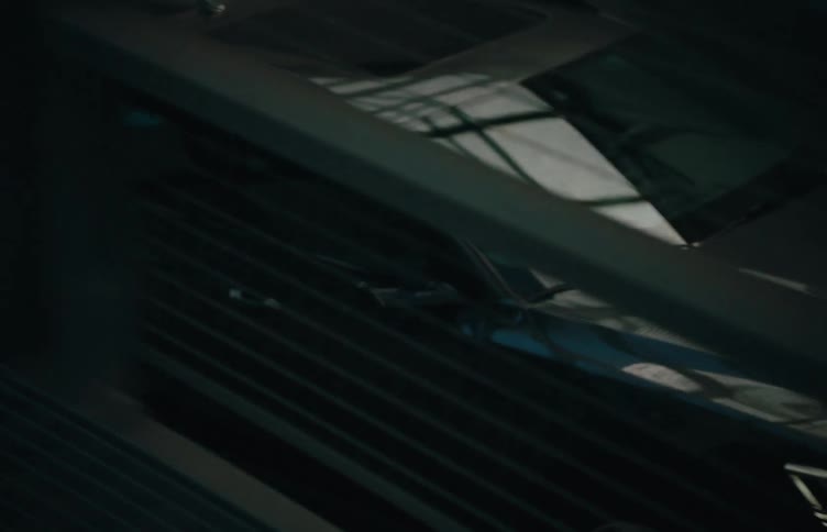 A sedan car drives across a steel bridge at midday