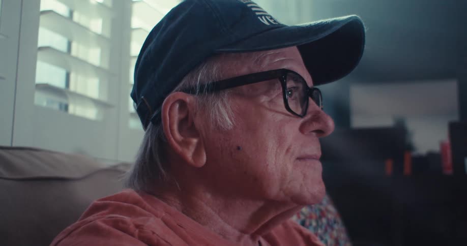Elderly man is sitting on a couch in his living room