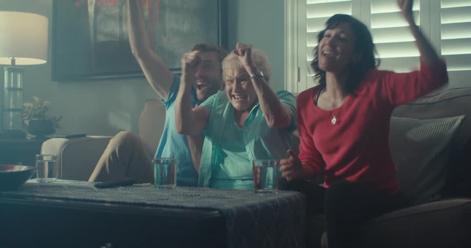 People cheer at the television while sitting on the couch