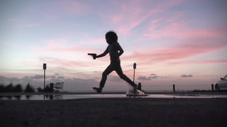 A child runs with a gun at sunset