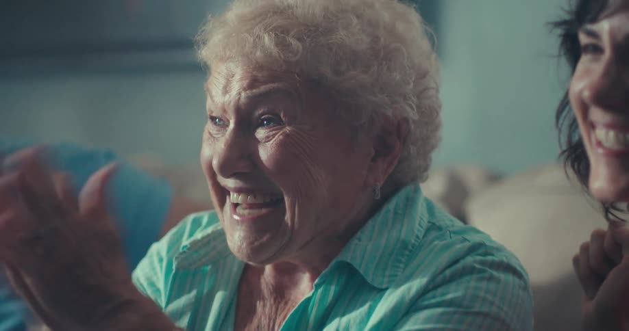 Family cheers and laughs while watching television together during the daytime