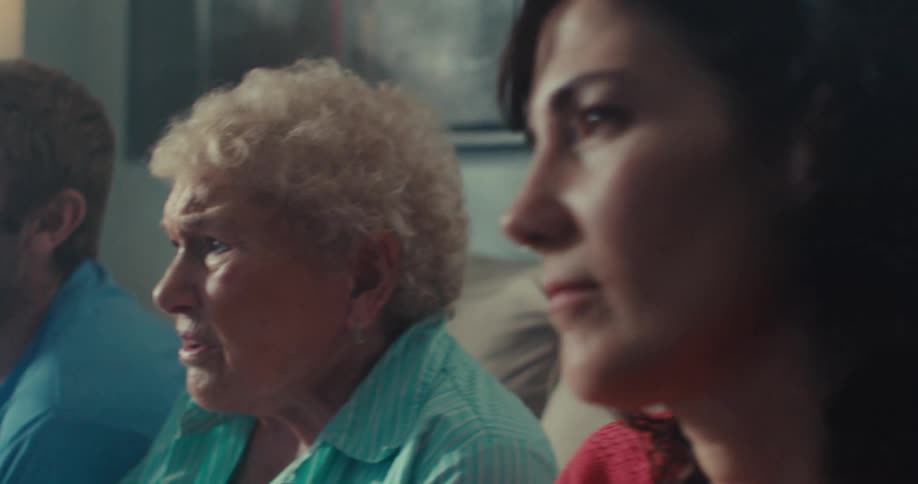 A man and two women talk while watching television