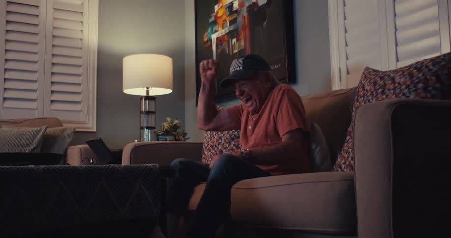 A man raises his arm and cheers at the tablet