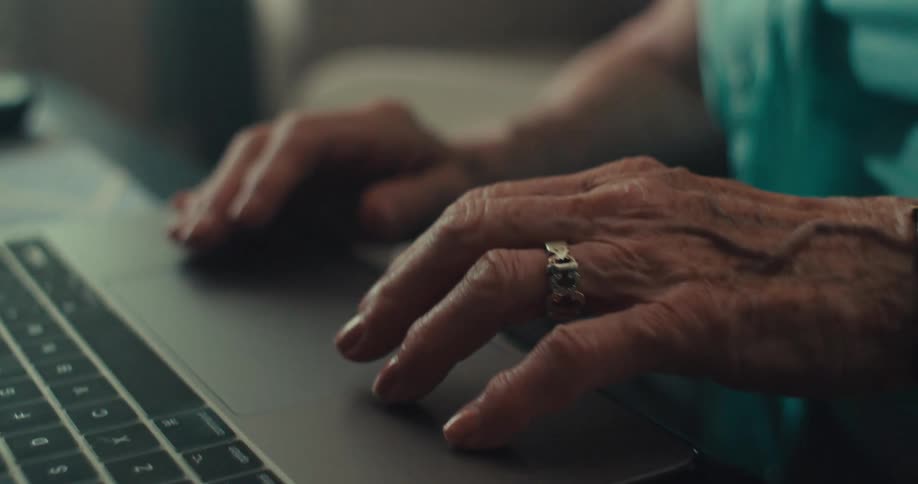 The woman is sitting at home using a laptop